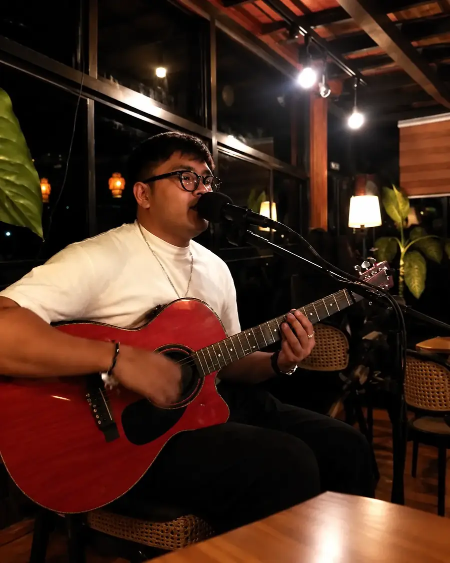 A singer with an acoustic guitar performing live at Jakarta